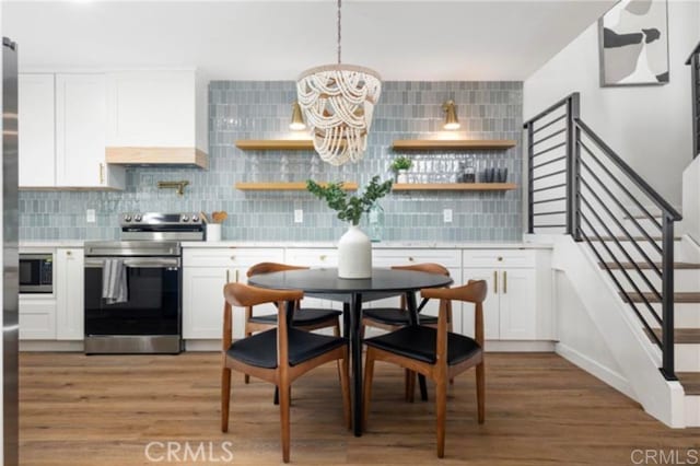 kitchen featuring tasteful backsplash, custom exhaust hood, appliances with stainless steel finishes, and white cabinets