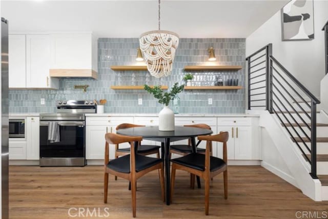 kitchen featuring stainless steel appliances, custom range hood, white cabinets, and decorative backsplash