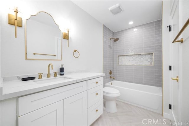 full bathroom featuring tiled shower / bath, vanity, and toilet