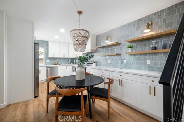 kitchen featuring pendant lighting, tasteful backsplash, white cabinets, stainless steel appliances, and light wood-type flooring