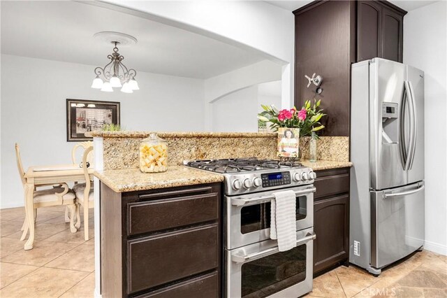 kitchen with dark brown cabinetry, stainless steel appliances, decorative light fixtures, and light stone countertops