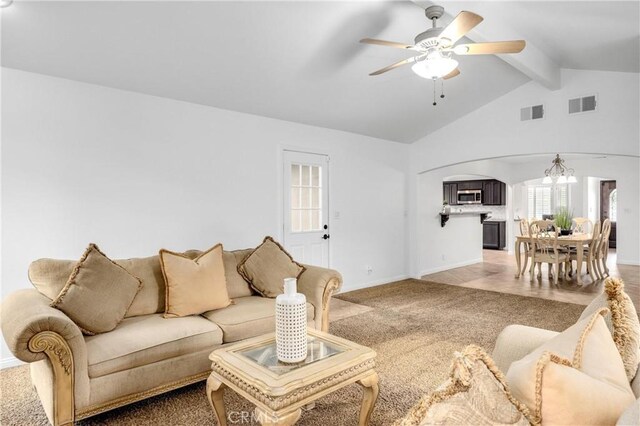 living room featuring ceiling fan with notable chandelier, lofted ceiling with beams, and carpet