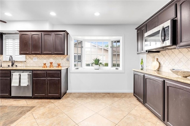 kitchen featuring stainless steel appliances, light tile patterned flooring, light stone countertops, and dark brown cabinets