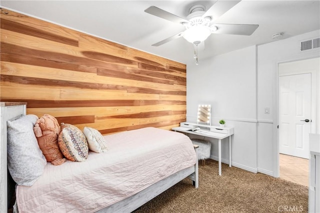 carpeted bedroom featuring ceiling fan and wood walls