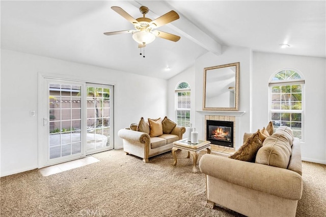 carpeted living room featuring a tiled fireplace, vaulted ceiling with beams, a wealth of natural light, and ceiling fan