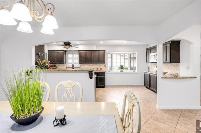 dining area with light tile patterned flooring and ceiling fan with notable chandelier