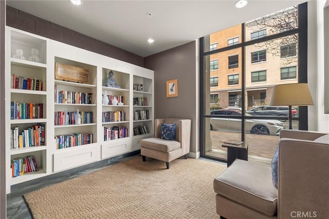 sitting room featuring built in features, floor to ceiling windows, and carpet