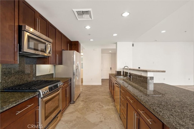 kitchen featuring appliances with stainless steel finishes, sink, dark stone countertops, and decorative backsplash