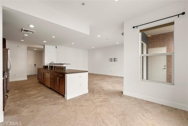 kitchen featuring an island with sink, appliances with stainless steel finishes, sink, and dark stone counters