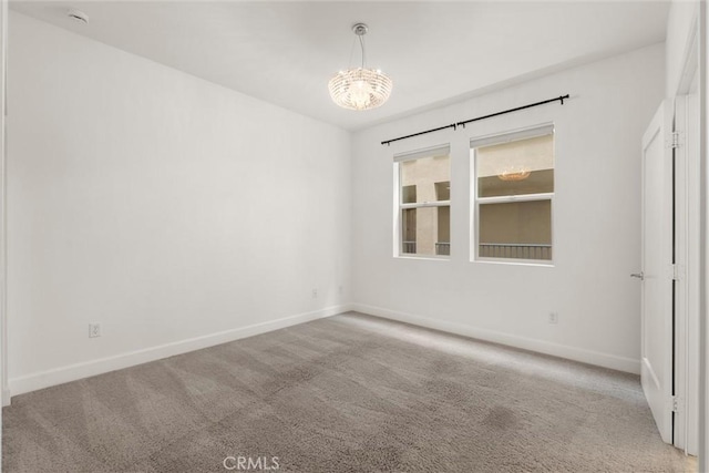 carpeted empty room featuring a notable chandelier