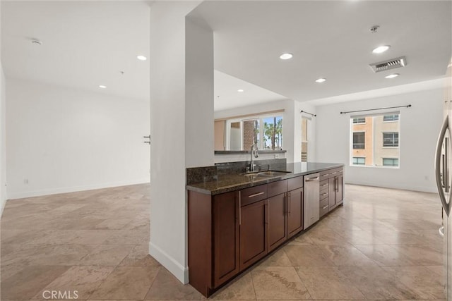 kitchen featuring dark brown cabinetry, sink, dark stone counters, and dishwasher