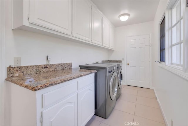 laundry room featuring light tile patterned floors, washing machine and dryer, and cabinets