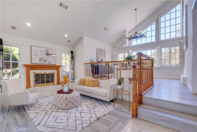 living room with an inviting chandelier, a healthy amount of sunlight, and high vaulted ceiling