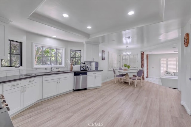 kitchen with sink, stainless steel dishwasher, a raised ceiling, pendant lighting, and white cabinets