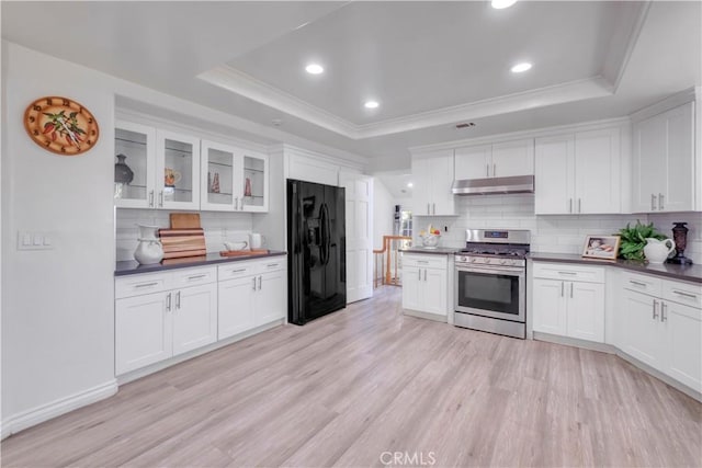 kitchen featuring black fridge, white cabinetry, a raised ceiling, and stainless steel gas range oven