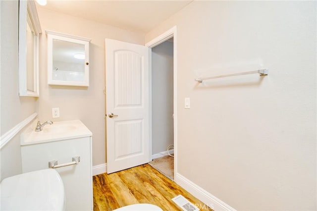 bathroom with hardwood / wood-style flooring, vanity, and toilet