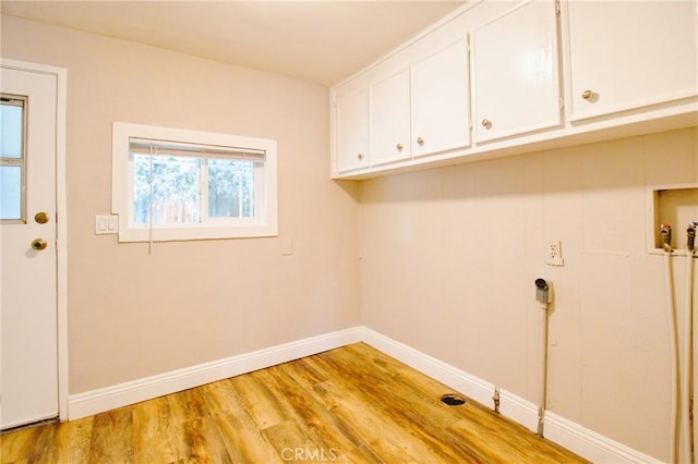 washroom featuring hookup for a washing machine, light hardwood / wood-style flooring, and cabinets