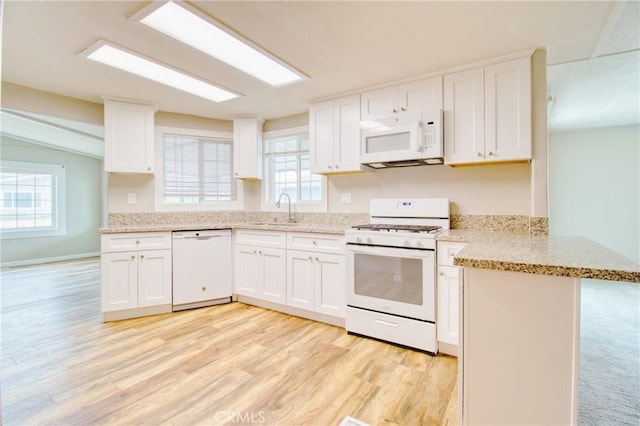 kitchen with white appliances, kitchen peninsula, sink, and white cabinets