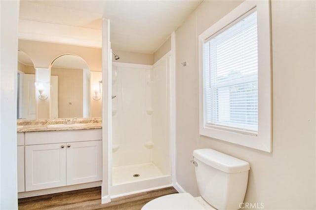 bathroom featuring vanity, toilet, hardwood / wood-style floors, and a shower