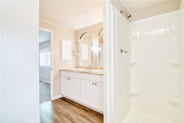 bathroom featuring hardwood / wood-style flooring, vanity, and a shower