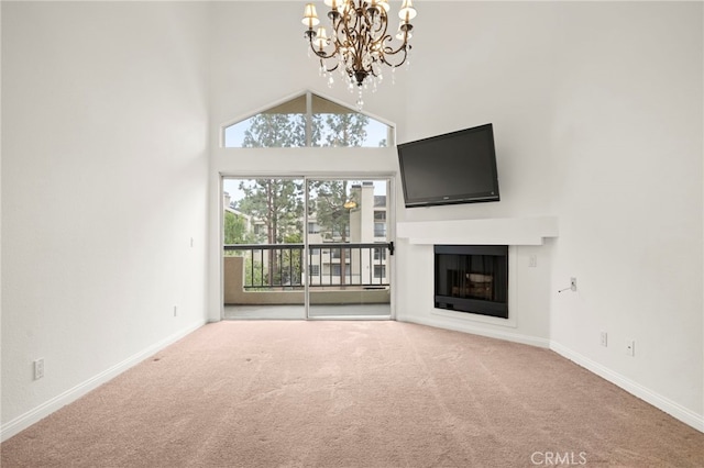 unfurnished living room with a glass covered fireplace, baseboards, carpet flooring, and a high ceiling