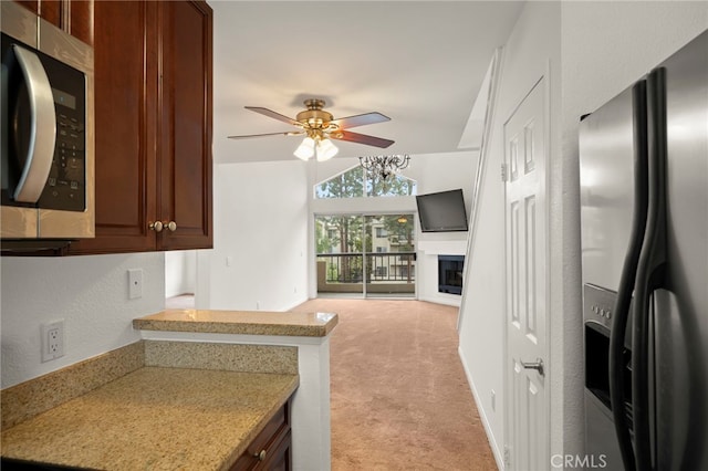 kitchen featuring light carpet, a ceiling fan, light countertops, appliances with stainless steel finishes, and a glass covered fireplace