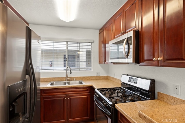 kitchen with appliances with stainless steel finishes, a sink, and a textured ceiling