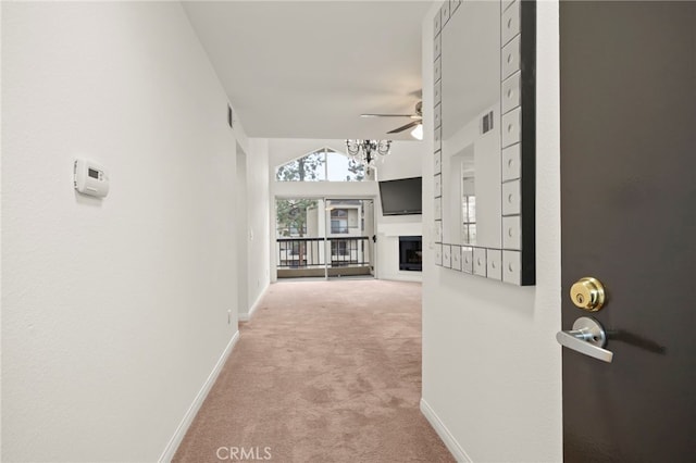 corridor with light carpet, vaulted ceiling, and baseboards