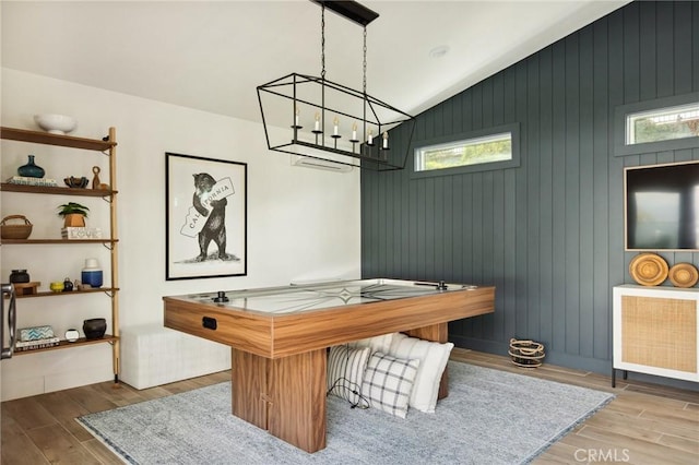 rec room featuring hardwood / wood-style flooring, lofted ceiling, and a chandelier