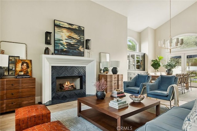 living room featuring a healthy amount of sunlight, a fireplace, high vaulted ceiling, and light hardwood / wood-style flooring