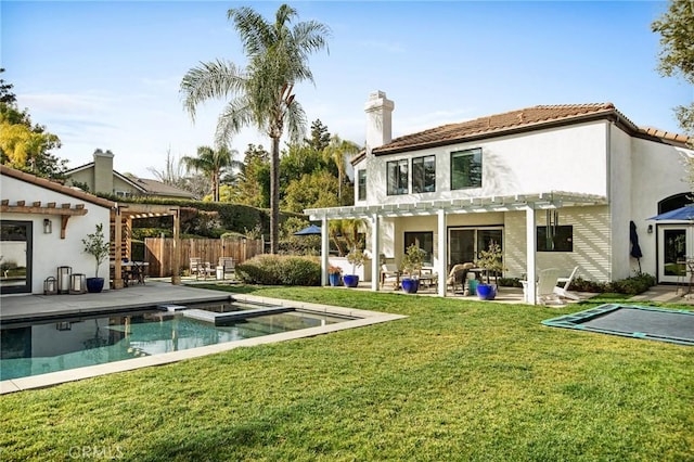 rear view of house with a patio area, a pergola, a pool with hot tub, and a lawn