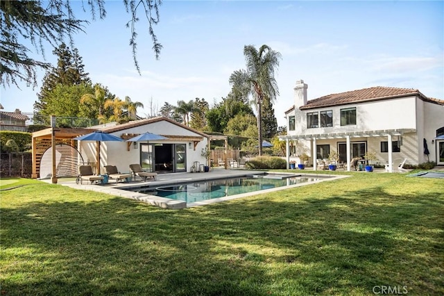 back of property featuring an outbuilding, a pergola, and a lawn