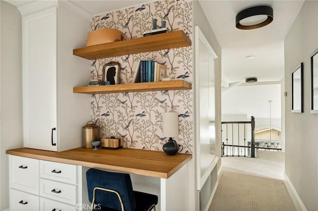 bar featuring white cabinetry, light carpet, and built in desk