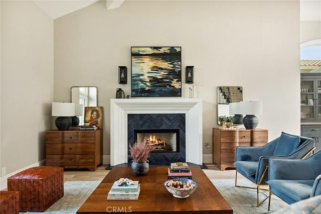 living room with lofted ceiling, a premium fireplace, and light wood-type flooring