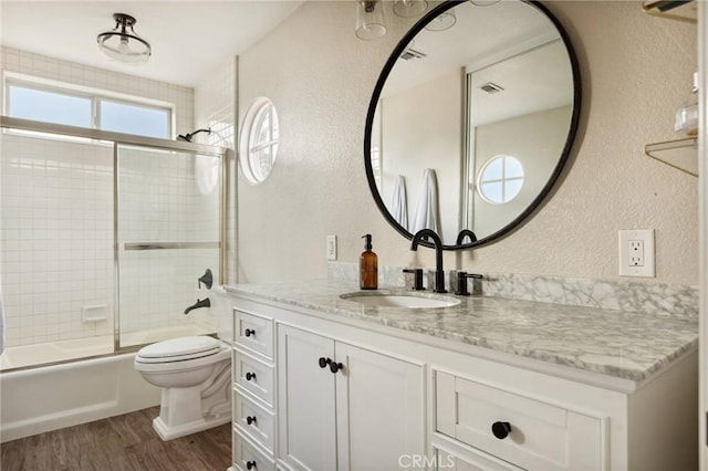 full bathroom featuring vanity, hardwood / wood-style floors, enclosed tub / shower combo, and toilet