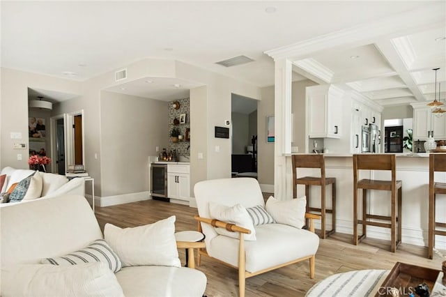 living room featuring coffered ceiling, light wood-type flooring, beverage cooler, and indoor bar