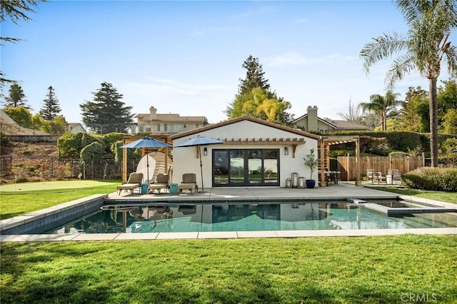 rear view of property with a fenced in pool, a yard, and a patio area