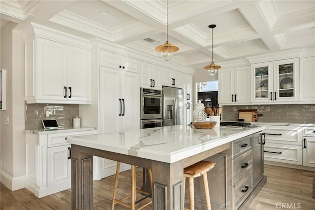 kitchen featuring a kitchen island, light stone countertops, appliances with stainless steel finishes, and white cabinetry