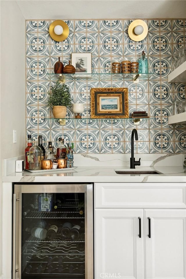 bar with white cabinetry, light stone countertops, sink, and wine cooler