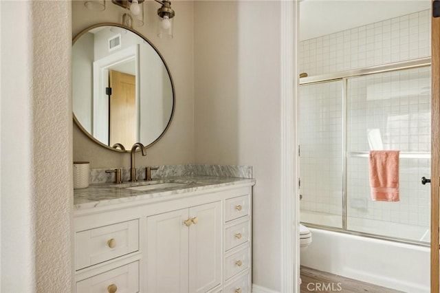 full bathroom with vanity, hardwood / wood-style floors, enclosed tub / shower combo, and toilet