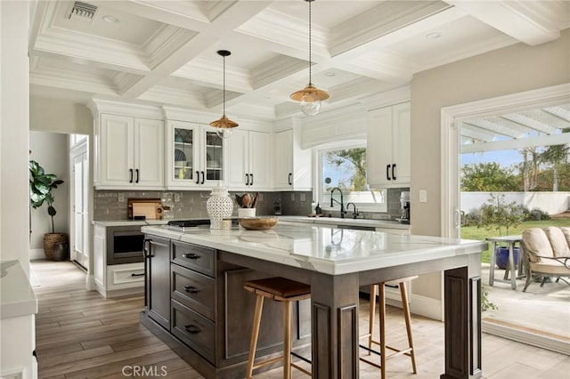 kitchen with beamed ceiling, a center island, pendant lighting, and white cabinets