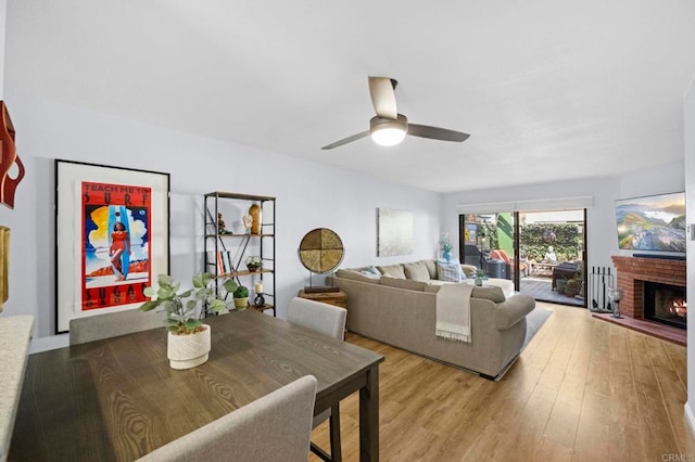 living room featuring a brick fireplace, light hardwood / wood-style flooring, and ceiling fan