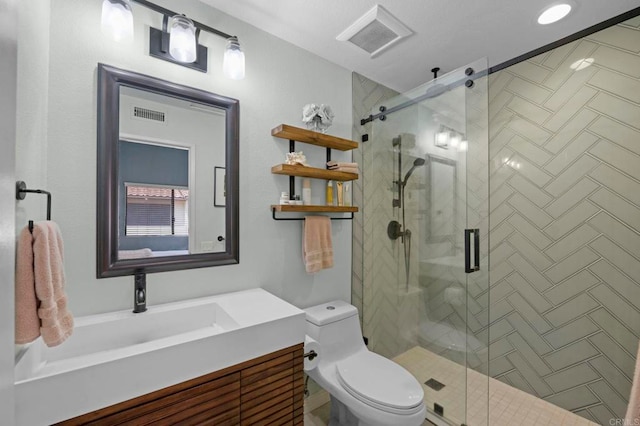 bathroom with vanity, a shower with shower door, and toilet