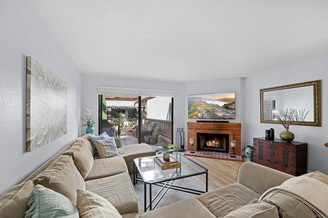 living room with a brick fireplace and hardwood / wood-style floors