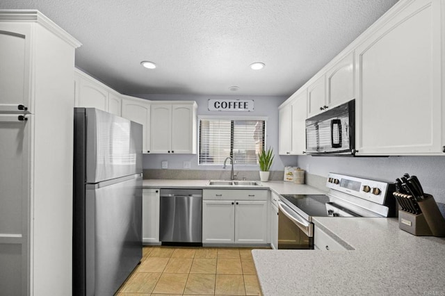 kitchen featuring sink, white cabinets, light tile patterned floors, stainless steel appliances, and a textured ceiling