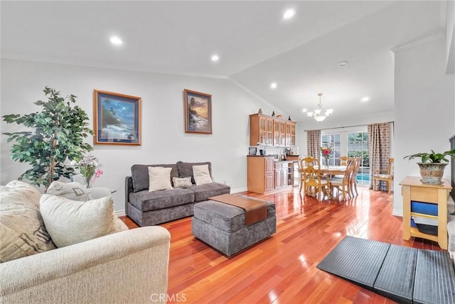 living room featuring an inviting chandelier, lofted ceiling, and light hardwood / wood-style flooring