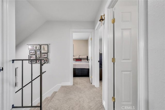 corridor with lofted ceiling and light colored carpet