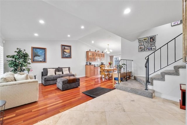 living room with lofted ceiling, light hardwood / wood-style floors, and an inviting chandelier