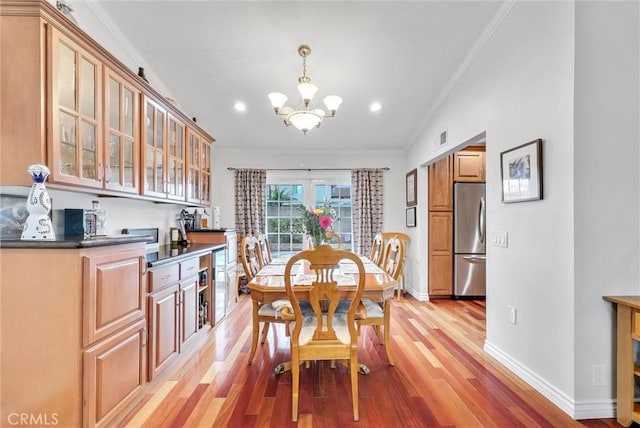 dining space with ornamental molding, a chandelier, and light hardwood / wood-style flooring