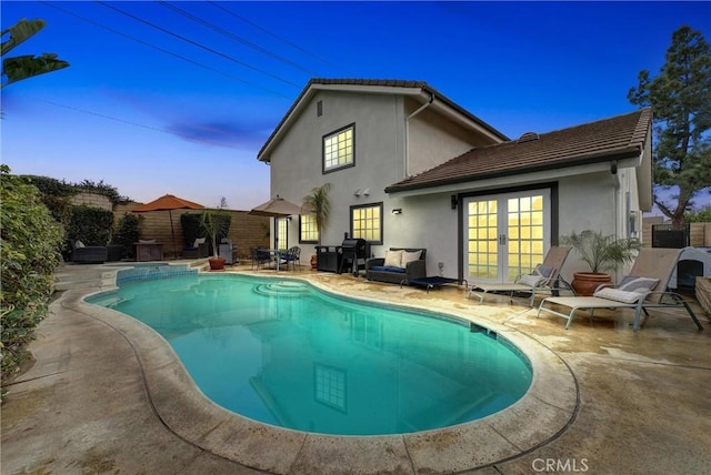 pool at dusk with a patio area and french doors